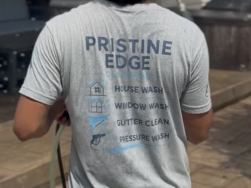 Pristine Edge Cleaning crew member pressure washing a home exterior